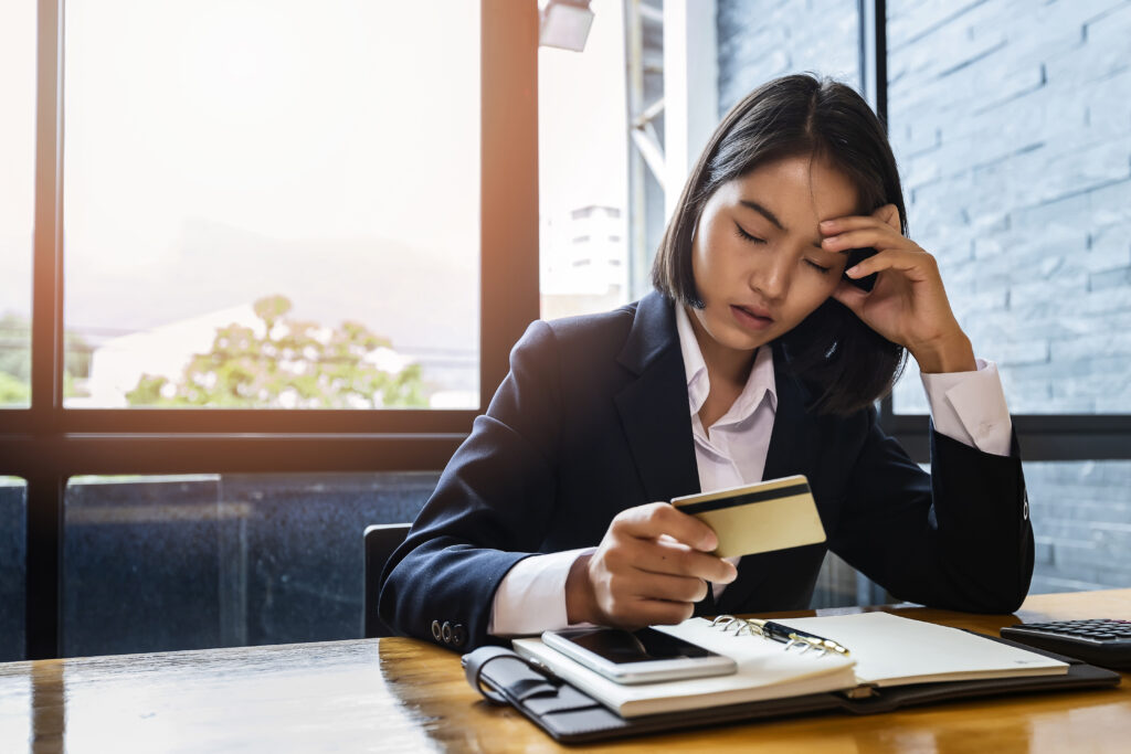 Stressful asian businesswoman with huge amount of credit card de