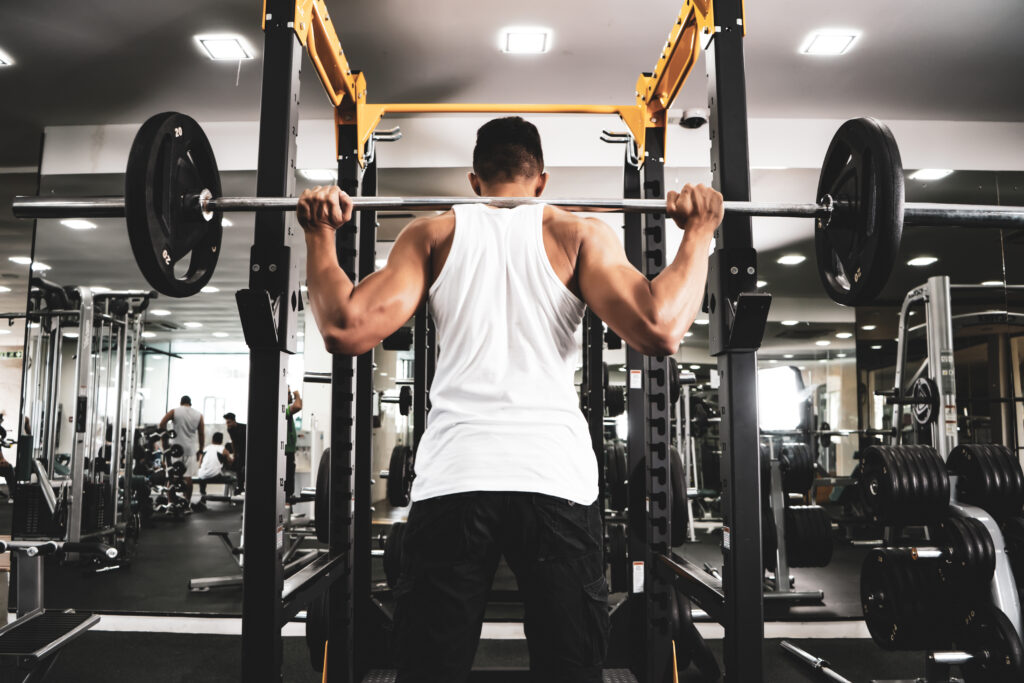Man at the gym. Execute exercise squatting with weight, in gym